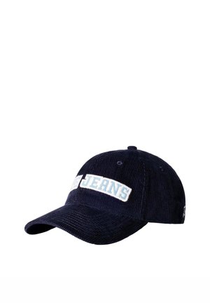 Berretto da baseball in velluto a coste blu navy con visiera curva e toppa bianca sul davanti con la parola "JEANS" in lettere azzurro chiaro.