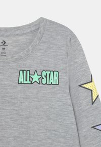 Szara koszula z długim rękawem z grafiką "ALL★STAR" w kolorze mięty z czarnym obrysem. Kolorowe gwiazdy akcentujące w żółtym i fioletowym na rękawach.