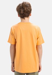 Camiseta de manga corta en algodón naranja brillante, con un clásico cuello redondo y un ajuste relajado, vista desde la parte trasera.