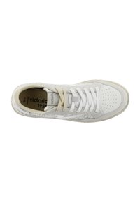Sneaker bianca con punta perforata, lacci crema e accenti beige. Presenta un motivo testurizzato e una suola in gomma. Numero di modello visibile all'interno.