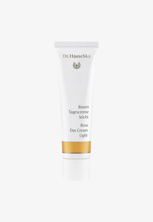 Tube blanc de la crème de jour légère à la rose de Dr. Hauschka avec des accents dorés et argentés, présentant du texte en allemand et en anglais sur le devant.