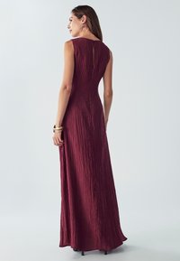 Maxi šaty v tmavo červenej farbe s textúrovanou, zvrásnenou tkaninou. bezramienkový dizajn s detalom kľúčovej dierky na chrbte. Elegantné a po zem.