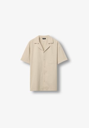 Chemise beige à manches courtes avec boutons, col de style camp et poche poitrine, présentée à plat sur un fond blanc.