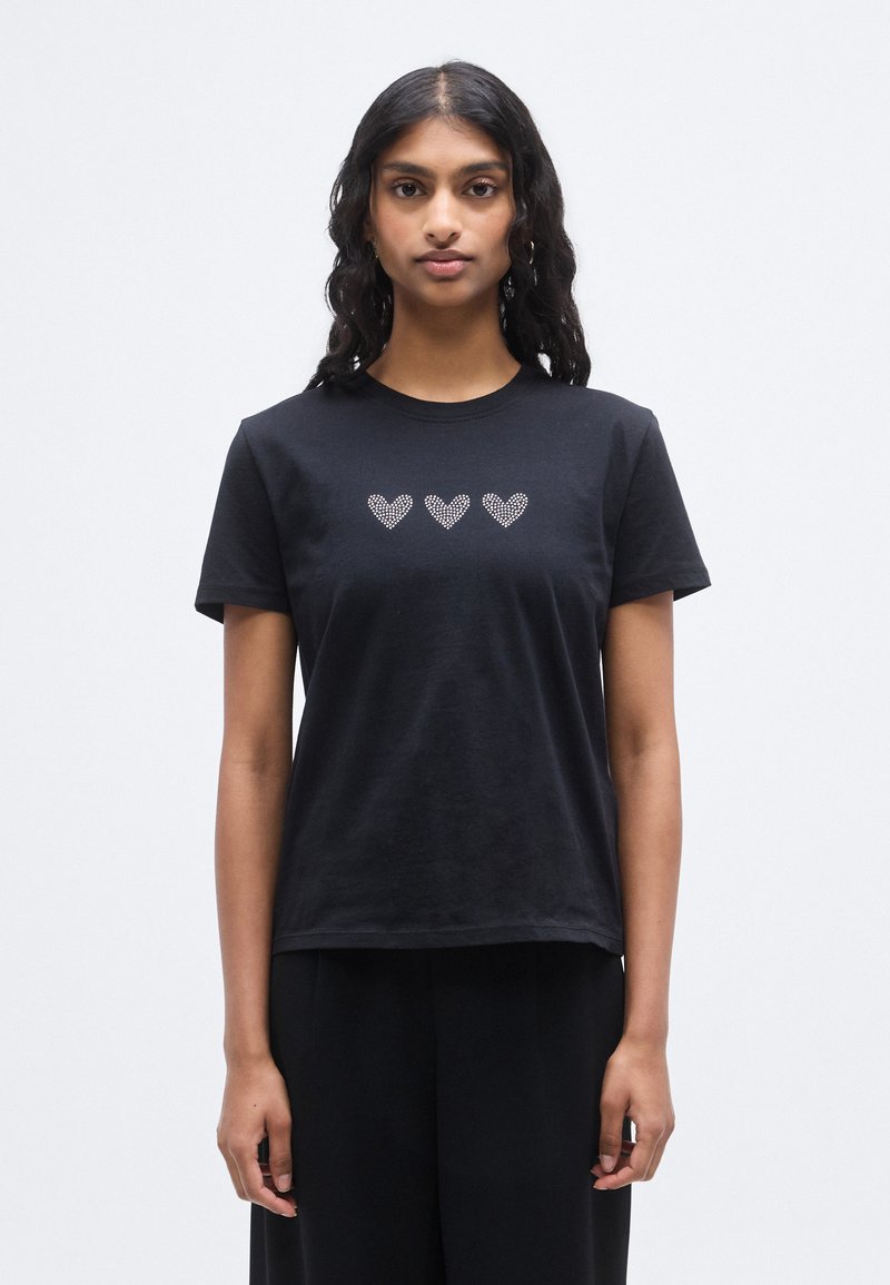 Μαύρο βαμβακερό t-shirt με στρογγυλή λαιμόκοψη και κοντά μανίκια, διακοσμημένο με τρεις καρδιές από μικρά στρας στο μπροστινό μέρος.