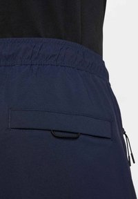 Marineblauwe korte broek van lichtgewicht stof, met een elastische tailleband, een achterzak met klep en een trekkoorddetail.