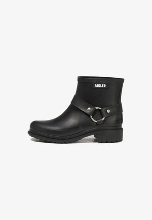 Black ankle boots made of rubber with a textured finish. Features a wide strap with a circular metal ring, durable outsole, and branded logo.