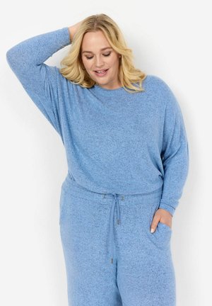 Completo loungewear blu chiaro e texture. La parte superiore ha una vestibilità comoda con maniche lunghe; i pantaloni hanno una vita elastica con coulisse e tasche.