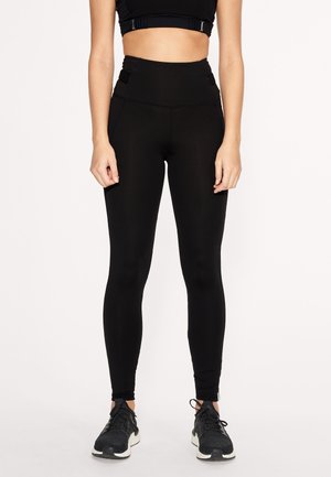 Leggings neri a vita alta realizzati in tessuto elasticizzato con una texture liscia, caratterizzati da cuciture laterali per un aspetto aderente e minimalismo nei dettagli.