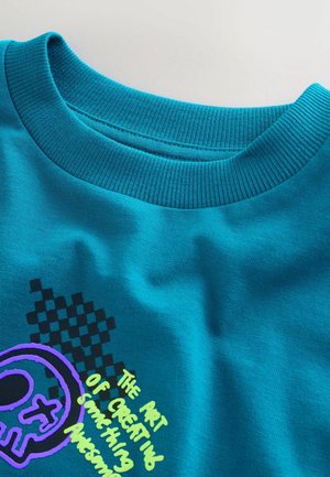 Turkio spalvos medvilniniai marškinėliai su ribuotu apvaliu kaklu, violetinėmis ir juodomis grafikos spaudomis bei languoto dizaino raštu.