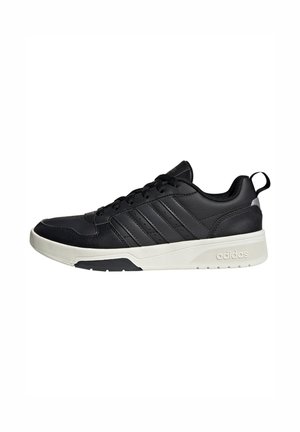 Zapatilla negra de corte bajo con suela blanca, cierre de cordones, diseño de tres rayas de Adidas y lengüeta en el talón.