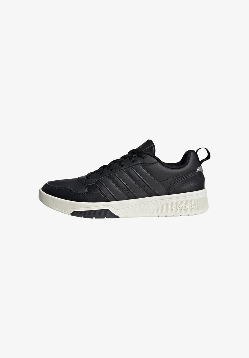 Baskets basses noires avec semelle blanche, fermeture à lacets, design trois bandes Adidas et languette au talon.