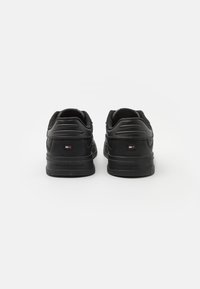 Czarne sneakersy z gładką skórzaną cholewką, wyściełanym kołnierzem i gumową podeszwą. Zawierają małe logo marki na pięcie oraz teksturowane akcenty.