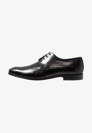Black leather dress shoe with a smooth finish, rounded toe, and four eyelets. Features a low, stacked heel and subtle stitching accents.