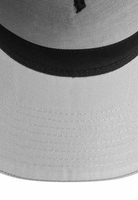 White bucket hat with a black inner band, visible stitching on wide brim, and mesh fabric on the crown.