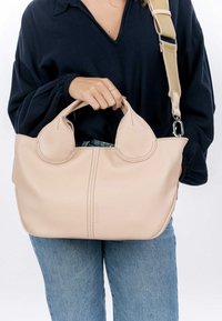 Borsa a mano in pelle rosa chiaro con accenti di manico arrotondato e tracolla staccabile; presenta dettagli nelle cuciture e una superficie morbida e texture.