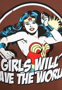 Brown T-shirt featuring a comic-style illustration of a female superhero with long blue hair, red accents, and bold text stating "GIRLS WILL SAVE THE WORLD."