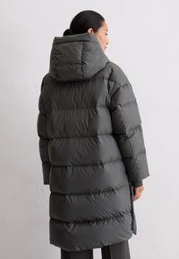 Dunkelgraue Daunenjacke mit Kapuze, horizontal gesteppt, mit langem Schnitt und elastischen Bündchen, die eine glatte, matte Oberfläche präsentiert.