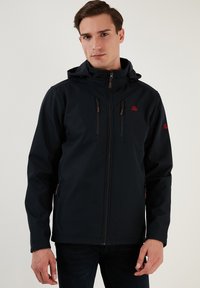 Melnā softshell jaka ar kapuci, kurai ir sarkani akcenti un rāvējslēdzēja kabatas. Gluda tekstūra ar plānu dizainu.
