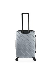 Maleta dura plateada con textura acanalada, mango retráctil negro y cuatro ruedas negras. Presenta el destacado logo de DKNY en un lado.