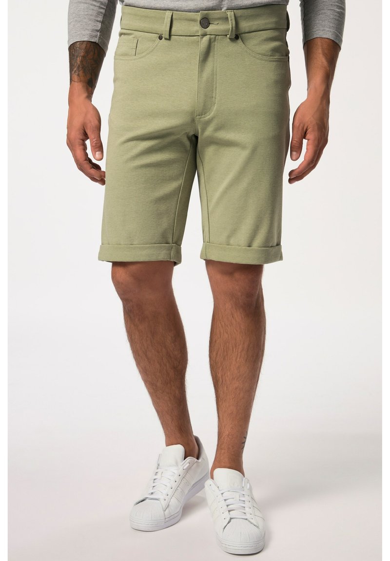 Pantaloni corte verde chiaro, fino al ginocchio, realizzati in tessuto morbido, con chiusura a bottone, orli arrotolati e tasche frontali. Abbinati a sneaker bianche.