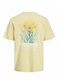 T-shirt giallo a maniche corte con una grafica di un fiore giallo e un cactus, accompagnata dalla scritta "Apache Hill" e dettagli sulla posizione sul retro.