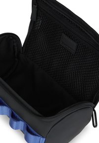 Μαύρη καλλυντική τσάντα με μπλε υφασμάτινα στοιχεία, διαθέτει κλείσιμο με φερμουάρ και μαλακή εσωτερική επένδυση. Περιλαμβάνει μια υφασμάτινη τσέπη από πλέγμα στο εσωτερικό.