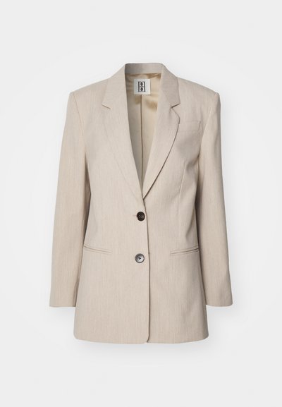 Beżowy żakiet dopasowany z klapami, z pojedynczym czarnym zapięciem na guzik i dwiema przednimi kieszeniami. Teksturowany materiał z subtelnym wzorem.