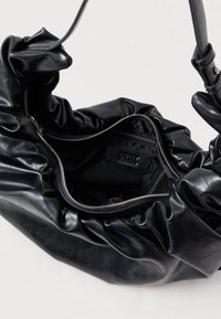 Fekete bőrtáska ráncolt kialakítással. Zipzárral záródik, belső részén egy "Diesel" felirattal ellátott zipzáras zseb található. Puha tapintású és rugalmas alakú.