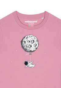 Helles rosa T-Shirt mit einer Schwarz-Weiß-Illustration eines Astronauten, der einen Mondballon vor einem sternenübersäten Hintergrund hält.