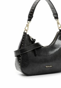 Zwarte handtas van gestructureerd kunstleer, met gouden studs langs de riem en een ritssluiting. Zijlogo detail zichtbaar.