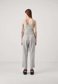 Débardeur sans manches gris clair à encolure carrée, assorti à un pantalon gris clair ample, doté d'une taille élastique et d'une texture subtile.