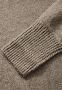 Beiger Strickpullover-Bündchen mit gerippter Textur, weicher Wollmischung, mit einer glatten Oberfläche und einheitlicher Naht.