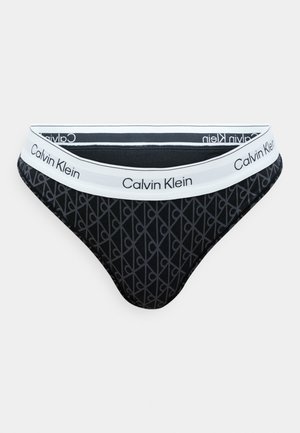 Black cotton thong with geometric pattern and white elastic waistband featuring "Calvin Klein" logo printed around it.