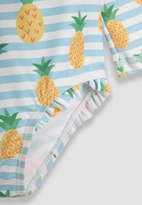 Maillot de bain avec un fond bleu clair présentant des ananas jaunes et des feuilles vertes, rehaussé de rayures horizontales blanches et de bords froncés.