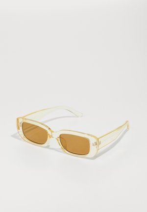 Óculos de sol retangulares com armações transparentes amarelas e lentes castanhas. As hastes apresentam uma marcação subtil e uma textura suave e brilhante.