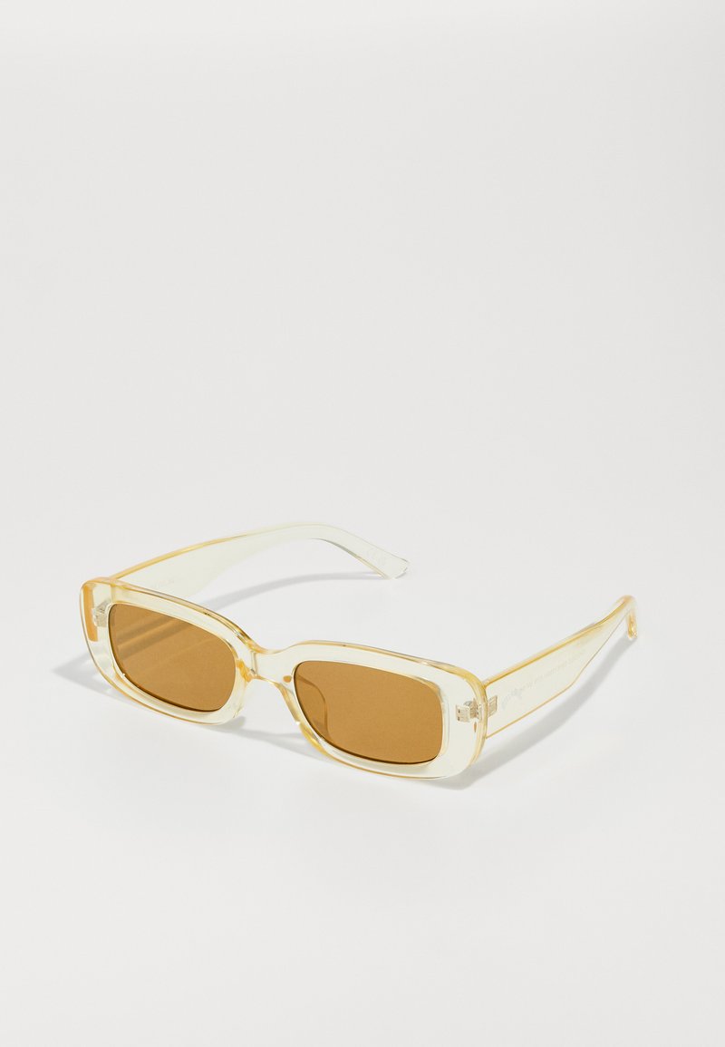 Gafas de sol rectangulares con montura amarilla transparente y lentes marrones. Las varillas presentan un sutil logotipo y una textura suave y brillante.