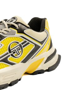 Sneaker da uomo con tomaia in mesh gialla e dettagli neri e grigi, design testurizzato e suola ammortizzata con un dettaglio giallo.