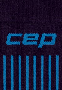 Die lila Kompressionssocken von CEP haben ein blaues Logo und vertikale Streifen. Das Material scheint gestrickt zu sein und hat eine glatte Textur.