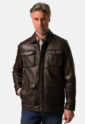 Brown leather jacket featuring a collared neck, four front pockets, a zip closure, and a smooth texture. Worn over a plaid shirt.