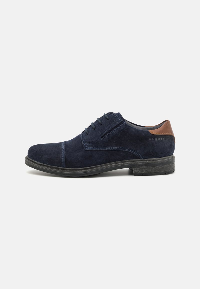 Scarpa in suede blu navy con accentatura in pelle marrone sul tallone e cuciture a contrasto. Suola piatta in gomma con finitura texturizzata.