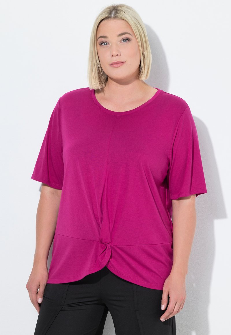Top fucsia de manga corta con escote redondo y detalle anudado en la cintura. Tejido suave y liso con un corte holgado.