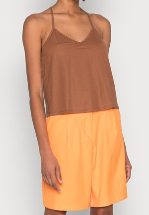 Brown cropped tank top with thin straps, paired with orange pleated shorts. The top has a V-neckline, made from soft, lightweight fabric.