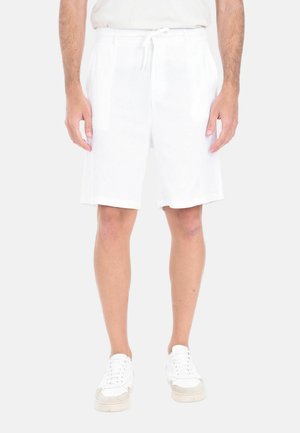 Shorts bianchi in lino con vita elastica e cordoncino, caratterizzati da un fit rilassato e una lunghezza fino al ginocchio. Indossati con sneakers bianche.