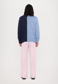 Sweater em azul e azul-marinho com bloco de cores, com barra canelada e decote redondo, combinado com calças largas em padrão xadrez gingham em rosa claro.