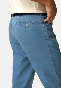Lichtblauwe chino's met een gestructureerde afwerking, voorzien van een achterzak met knoopsluiting en een gevlochten zwarte riem.