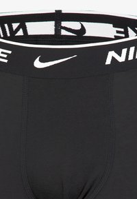 Schwarze Nike-Unterwäsche mit einem breiten elastischen Bund und weißem Branding sowie glattem, dehnbarem Stoff; beinhaltet flache Nähte für zusätzlichen Komfort.