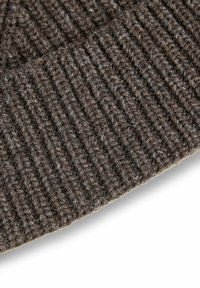 Beanie marrone lavorato a maglia caratterizzato da una texture a coste, realizzato in morbida lana. Il tessuto presenta un aspetto leggermente fluffy con fibre visibili.