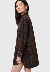Abito camicia in stampa leopardata realizzato in tessuto morbido, con colletto, maniche lunghe e orlo curvo con dettagli di bottoni dorati.
