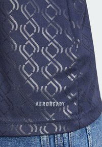 Laivastonsininen urheilupaita, jossa on vaaleanharmaa geometrinen kuvio. Varustettu "AEROREADY" -brändäyksellä valkoisena helman kohdalla. Valmistettu kosteudenkestävistä kankaista.