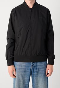 Schwarze Bomberjacke aus leichtem Stoff, mit Frontreißverschluss, Seitentaschen, gerippten Bündchen und elastischem Saum. Einfaches, schmuckloses Design.